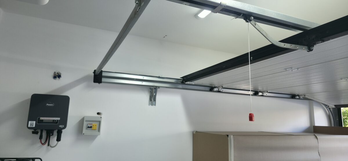Motorizzazione di una porta da garage con guide a soffitto e centralina installata, intervento eseguito da InstallGramm