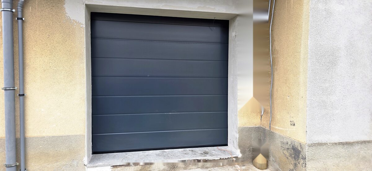 Porta da garage sezionale antracite montata in un vano esistente, esempio di lavoro agevolabile con il bonifico parlante